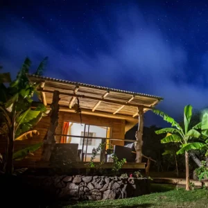 Wooden facade and terrace of the Kau Pora bungalow at night, under a starry sky.