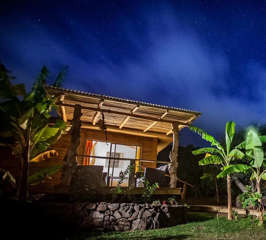Wooden facade and terrace of the Kau Pora bungalow at night, under a starry sky.