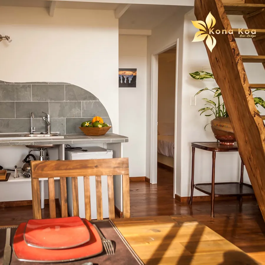 Kitchen corner of a bungalow at Kona Koa Eco Lodge with table, sink and raw wooden stairs.