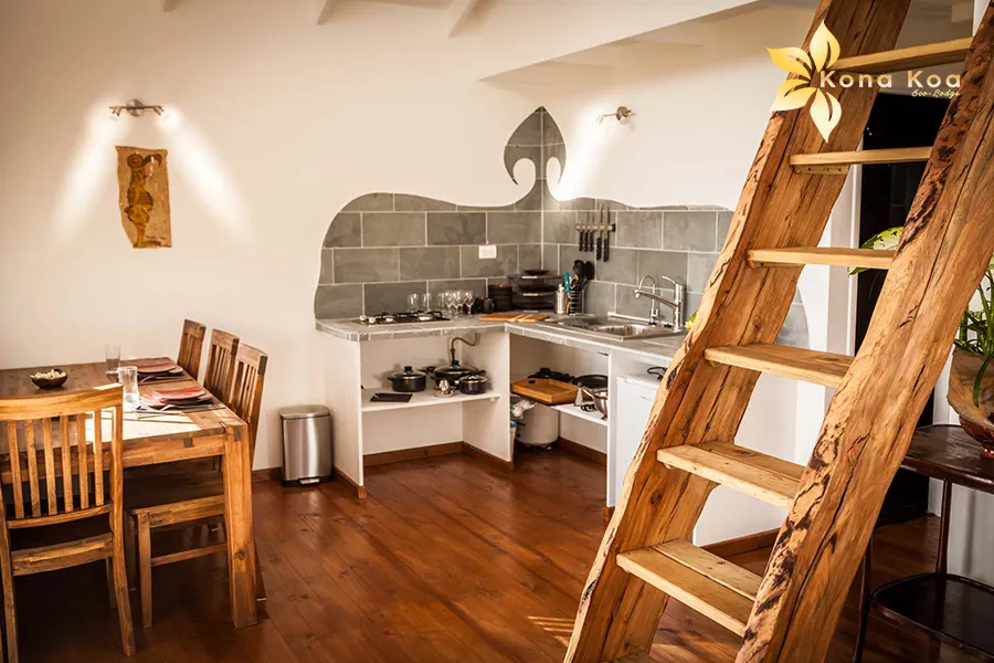 Overall view of a bungalow kitchen at Kona Koa Eco Lodge, with sink, counter and shelf.