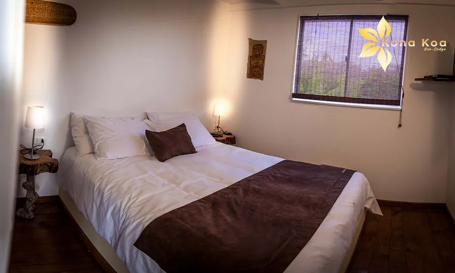 Double bed in a bungalow at Kona Koa Eco Lodge, with mosquito net and wooden headboard.