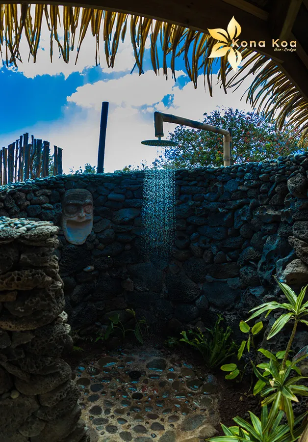 Open-air shower in the Haka Nini bungalow, enclosed by lava stone walls and plants.
