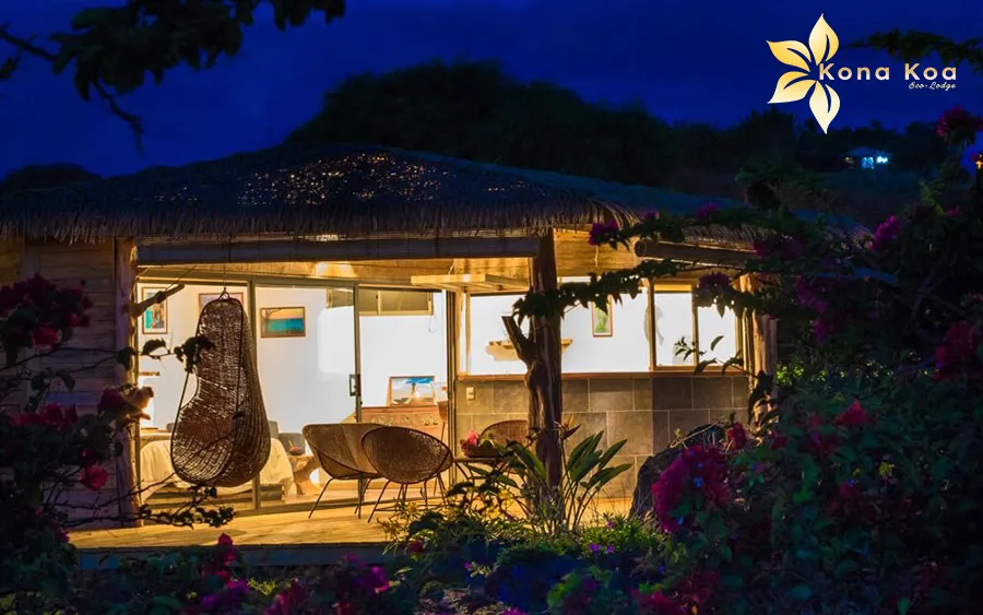 Night view of the Haka Nini bungalow with its thatched roof and lights.