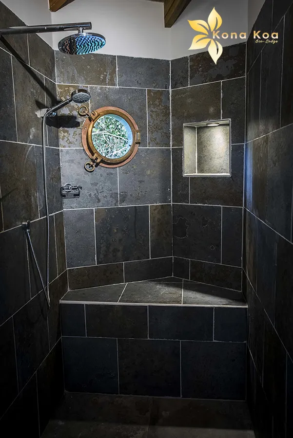 Design bathroom with stone shower and porthole window in a bungalow, Kona Koa Eco Lodge.