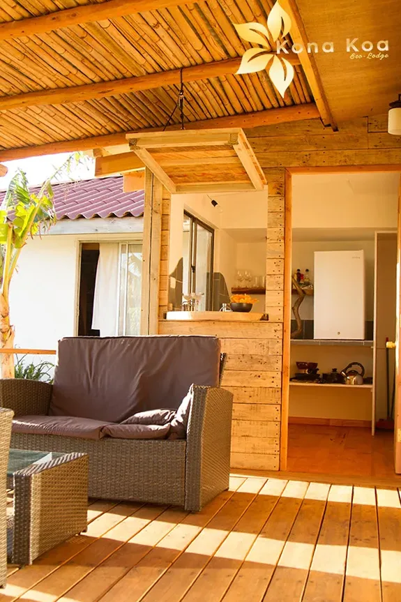 Terrace of the Kau Pora bungalow with outdoor sofa and a bar opening onto the kitchen.