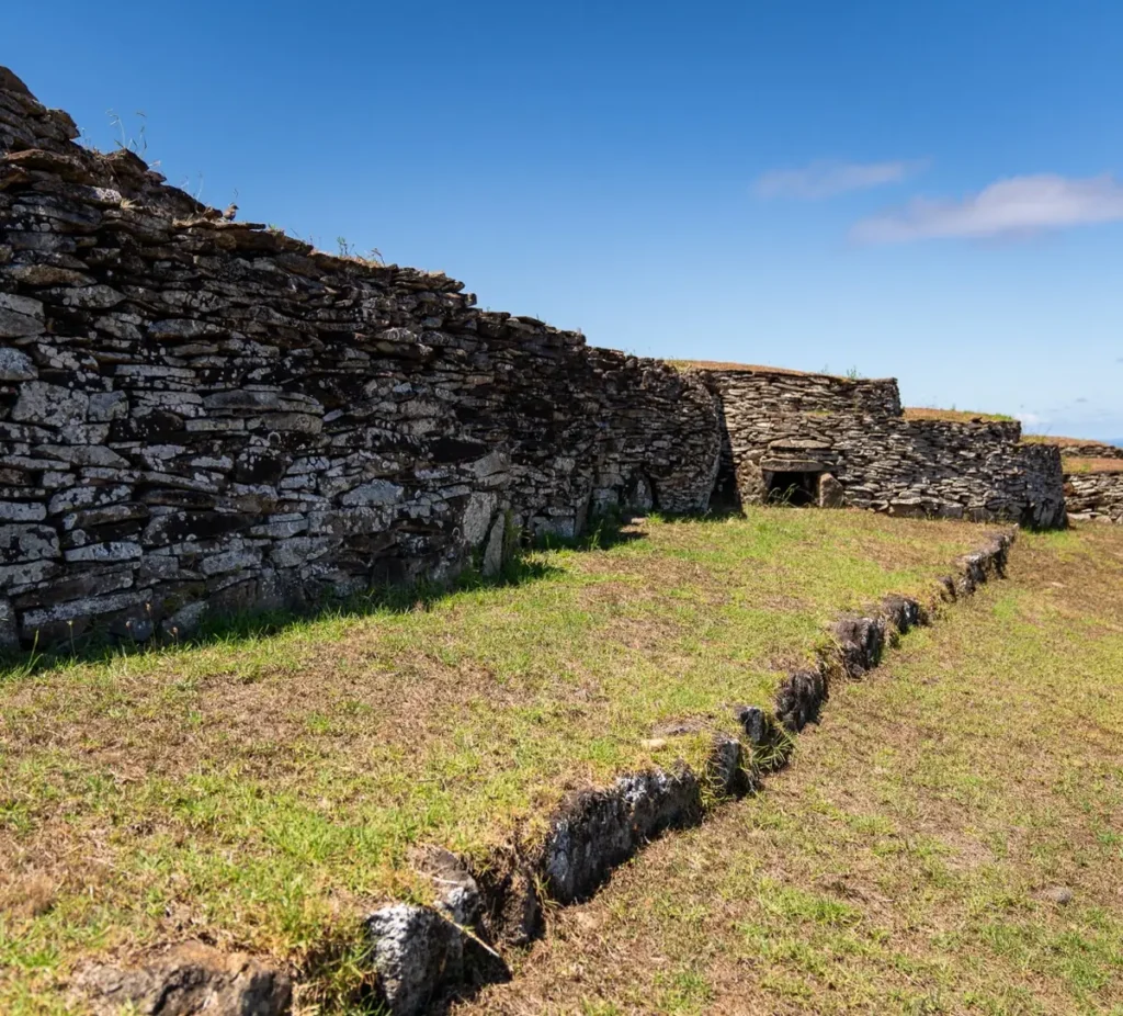 The stone houses of the Orongo ceremonial village lined along the ridge, the Pacific Ocean beyond.