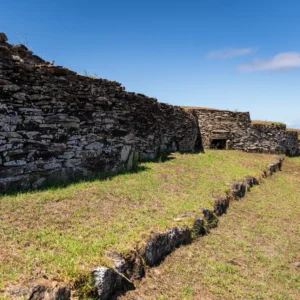 The stone houses of the Orongo ceremonial village lined along the ridge, the Pacific Ocean beyond.