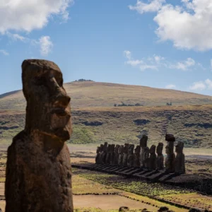 The fifteen moai of Ahu Tongariki on their platform, seen from the hillside, with a lone moai in the foreground.