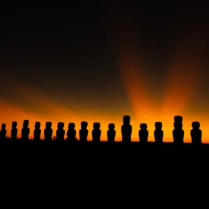 The fifteen moai of Ahu Tongariki silhouetted against an orange sky at sunrise.