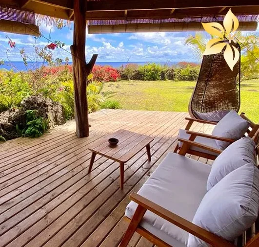 Wooden terrace of a bungalow at Kona Koa Eco Lodge with garden furniture and sea view.